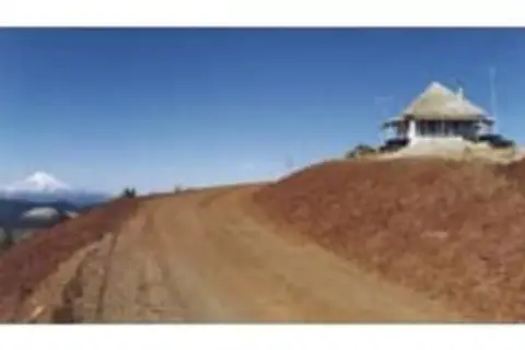 A dirt road leads up to a building on a hill.