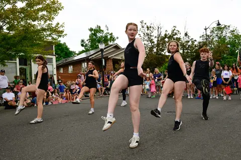 A group of dancers perform in the street in front of a crowd.