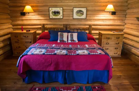 A rustic bedroom with a large log bed and wooden nightstands.