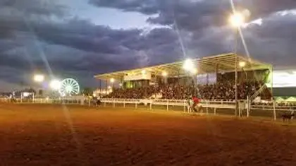A large crowd gathered in the grandstand at an outdoor arena at dusk.