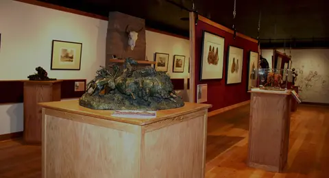 An interior museum exhibit featuring sculptures and framed artwork.