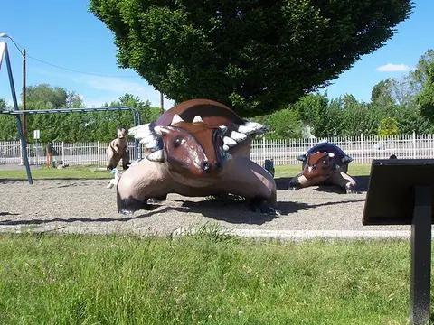 A photograph shows dinosaur statues on a playground.