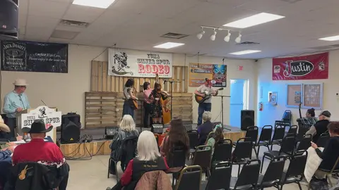 A band performs on a small stage in front of an audience in a hall.