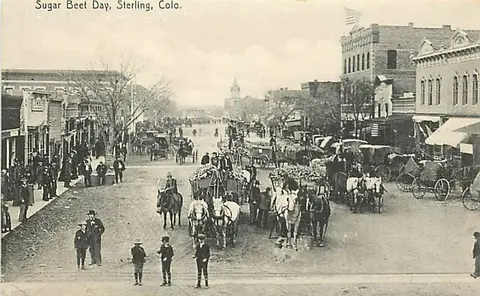An old photograph showing a street scene with horse-drawn carriages and people.