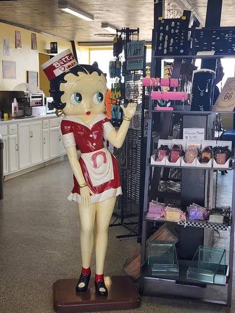 A life-sized figurine of a retro character stands inside a gift shop.
