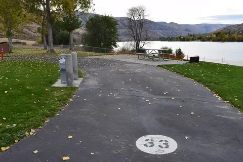 A paved campsite area next to a river with a picnic table and number 33 painted on the ground.