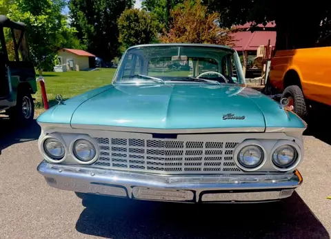 A teal and white classic car parked outside.