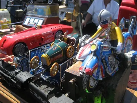 A collection of vintage tin toys including a motorcycle, cars, and a train displayed on a table.