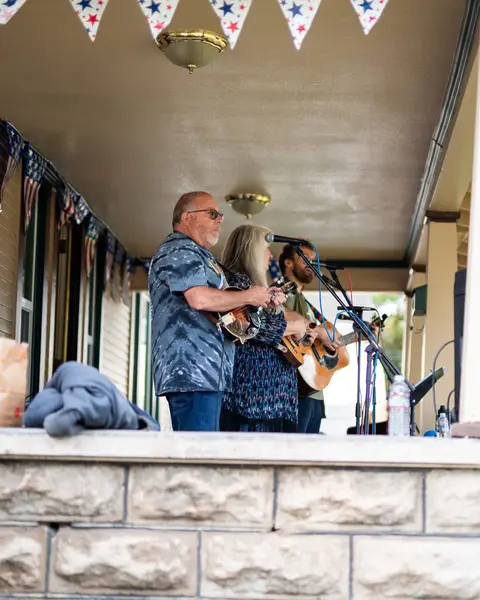 A group of musicians performing on a porch decorated with bunting.
