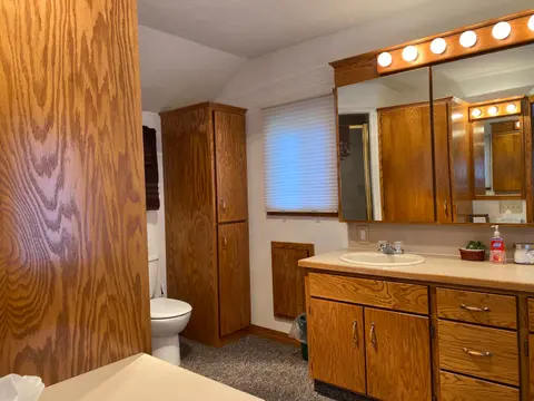 A bathroom featuring oak cabinetry and a sink.