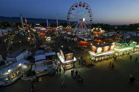 An elevated view of a crowded carnival at night with illuminated rides and food booths.