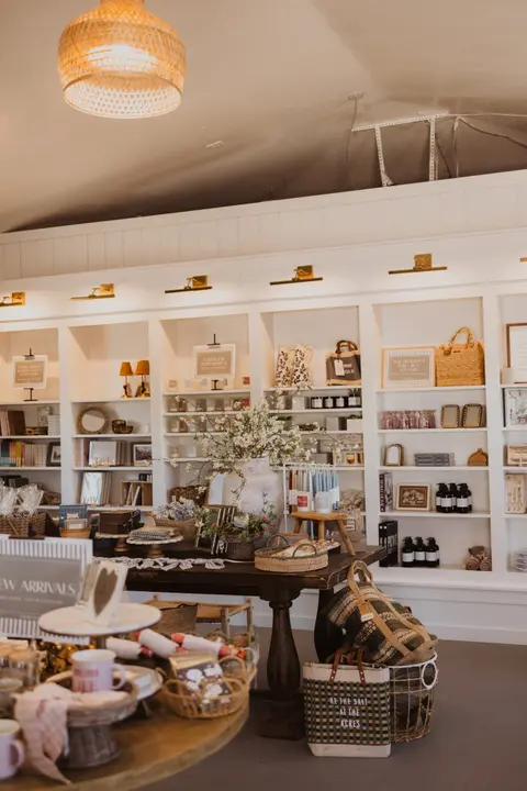 An interior view of a retail shop with white shelves and displays of various goods.