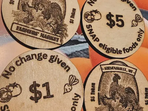 Four wooden tokens with printed market designs and denominations.