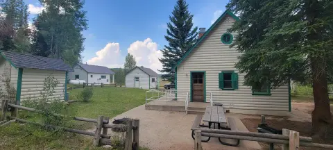 A view of several cabins on a sunny day with trees and grassy areas.