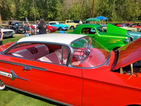A classic red car is parked at an outdoor car show.