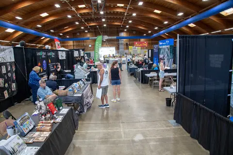 An indoor hall hosting an event with booths and attendees.