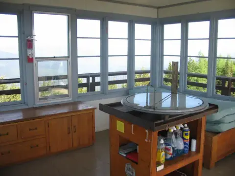 An interior view of a fire lookout tower with windows all around.