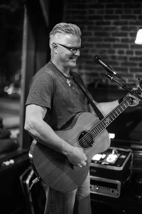 A man playing an acoustic guitar indoors.
