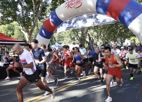 A crowd of runners participating in a race passing under an inflatable arch.