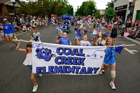 Children carry a banner in a street parade.