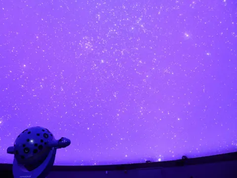 A planetarium projector displays a starry sky on a dome ceiling.