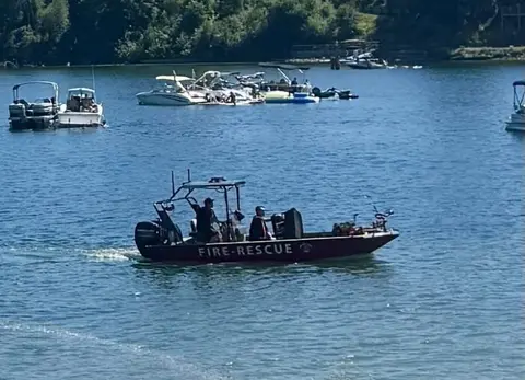 A fire-rescue boat on a body of water with other boats in the background.