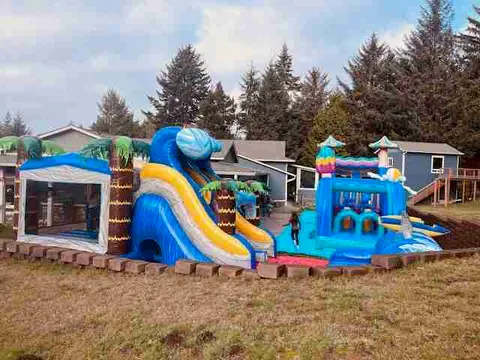 Inflatable bounce houses and water slides set up in a backyard.
