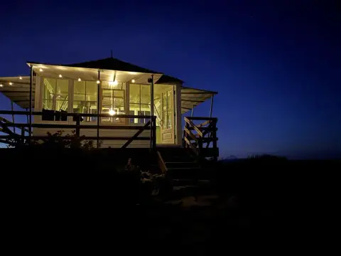 A brightly lit lookout cabin at dusk.