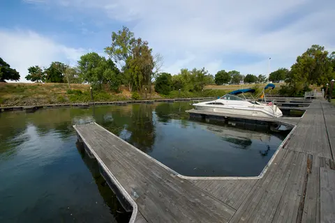 A boat docked at a wooden pier on a body of water.