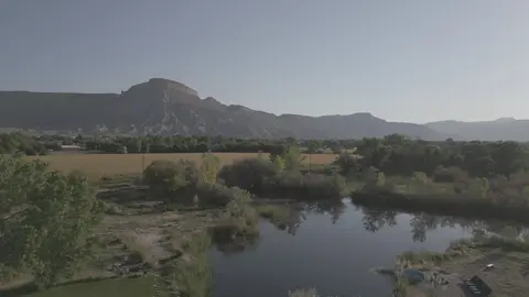 A scenic view of a pond with mountains in the background.