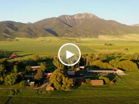 An aerial view of a farm nestled in a valley with mountains in the background.