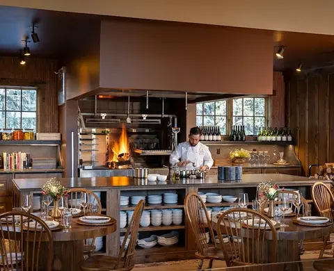 A chef working in a restaurant kitchen with a wood fire grill.