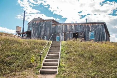 An exterior view of a rustic wooden building with a staircase leading up to it.