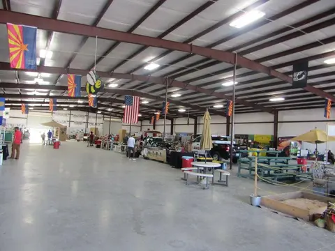 The interior of a large metal building with booths and flags set up inside.
