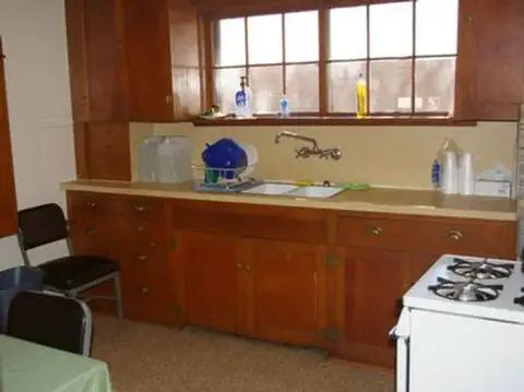 A photograph of a kitchen with wooden cabinets and a double sink under a window.
