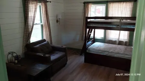 A photograph shows the interior of a bedroom with bunk beds and a sofa.