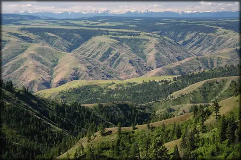 A scenic landscape shows rolling hills, valleys, and distant mountains.