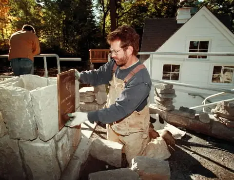A man working on a stone structure outdoors.