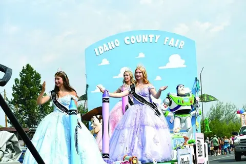 A parade float features royalty wearing crowns and sashes next to Toy Story characters.
