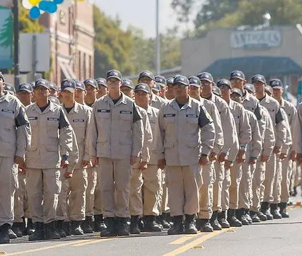 A group of people in uniform marching in formation outdoors.