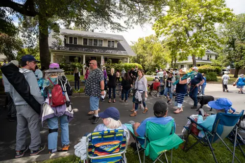 A crowd of people gathered on a residential street in front of a house.