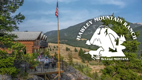 A wooden lodge deck overlooking a mountain landscape with guests dining.