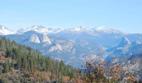 A scenic view of distant snowy mountains and forested hills.