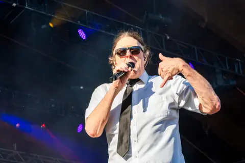 A singer performs on stage wearing a white shirt and sunglasses.