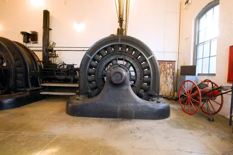 A large black generator and other industrial machinery inside a historic interior room.