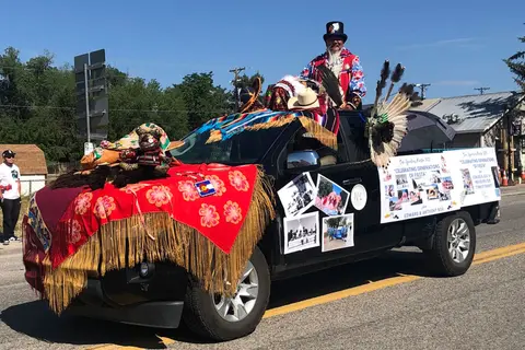 A decorated truck in a parade with a person standing in the bed.