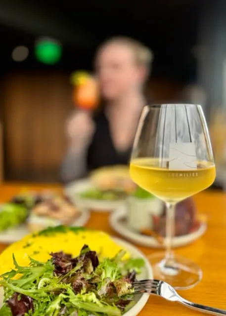 A glass of white wine and a plate of food at a restaurant table.