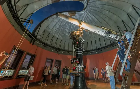 People view a large telescope inside an observatory dome.