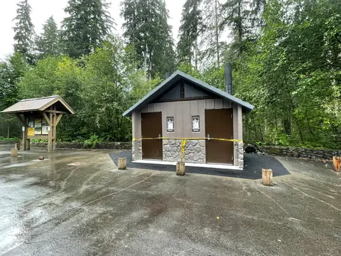 A public restroom building in a forest park surrounded by trees.