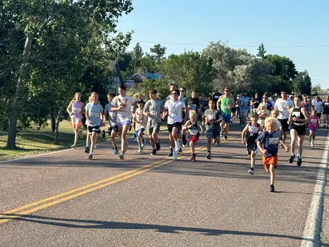 A large group of people running down an asphalt road.